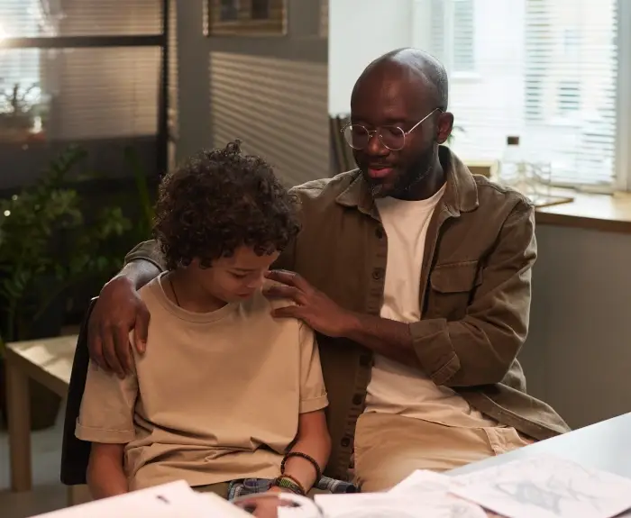concerned-father-embracing-son-with-adhd-sitting-in-his-office
