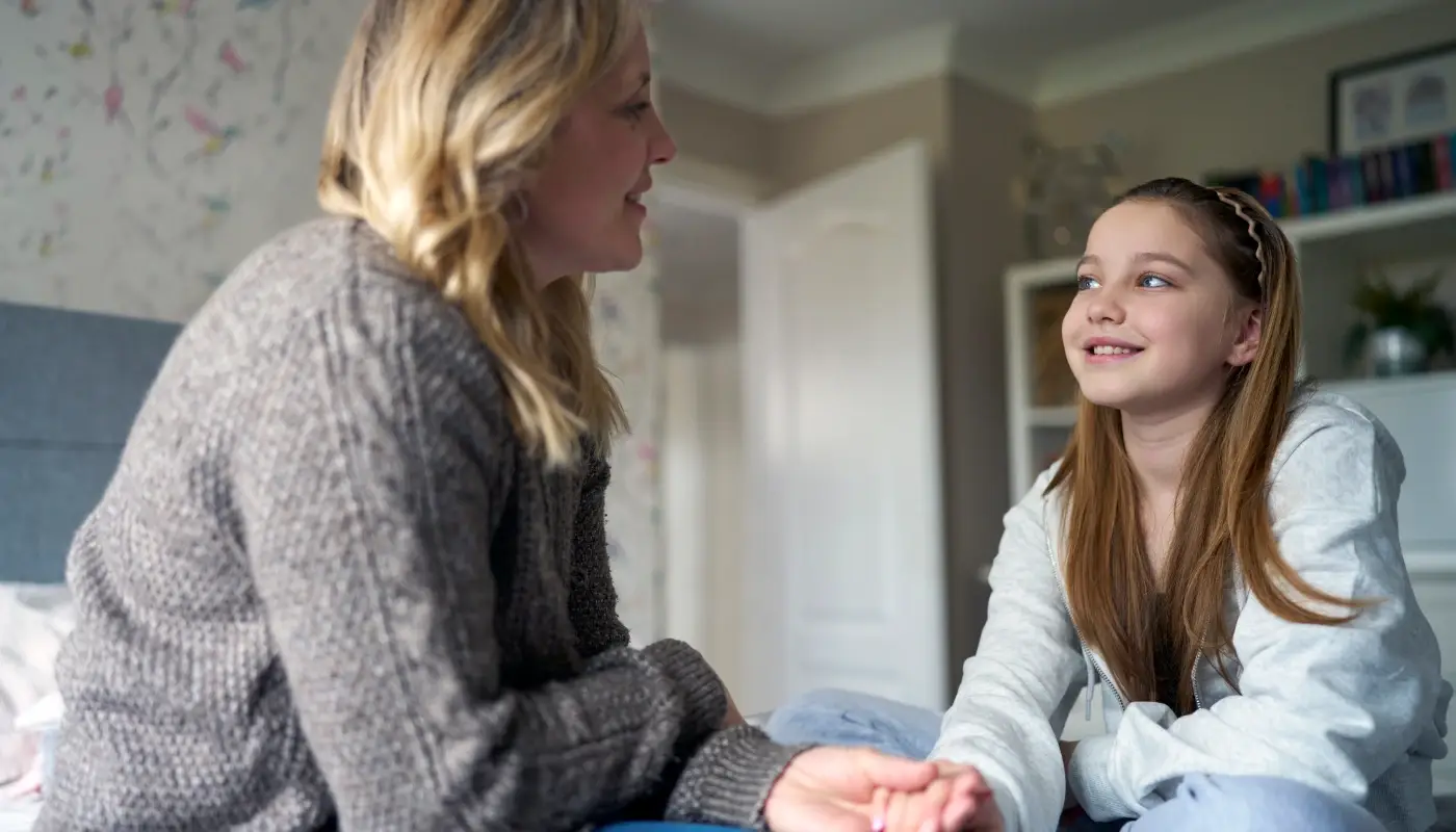 mother-supporting-daughter-with-adhd-holding-her-hand-sitting-on-her-bed