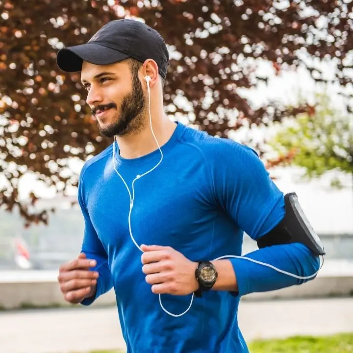 Man jogging outdoors with earphones on and holding a steady pace.