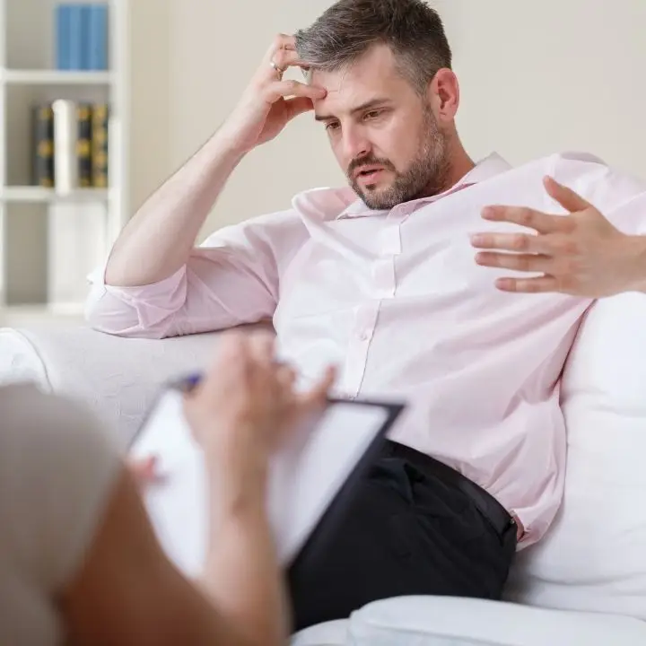 Man speaking with therapist during counseling session about anxiety symptoms.