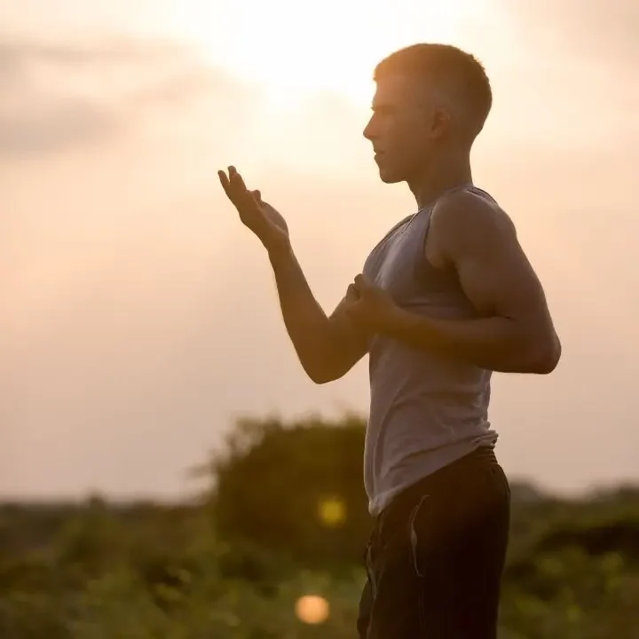 Man practicing mindful breathing outdoors at sunset as part of anxiety treatment.