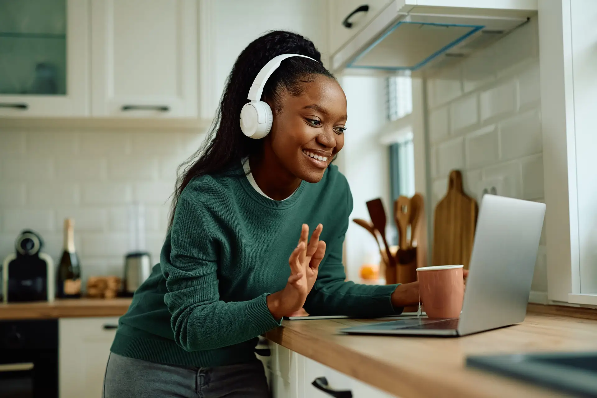 Happy African American woman using laptop and greeting therapist on a video call int he kitchen