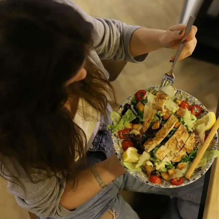 Woman eating a balanced salad with grilled chicken to support ADHD diet.