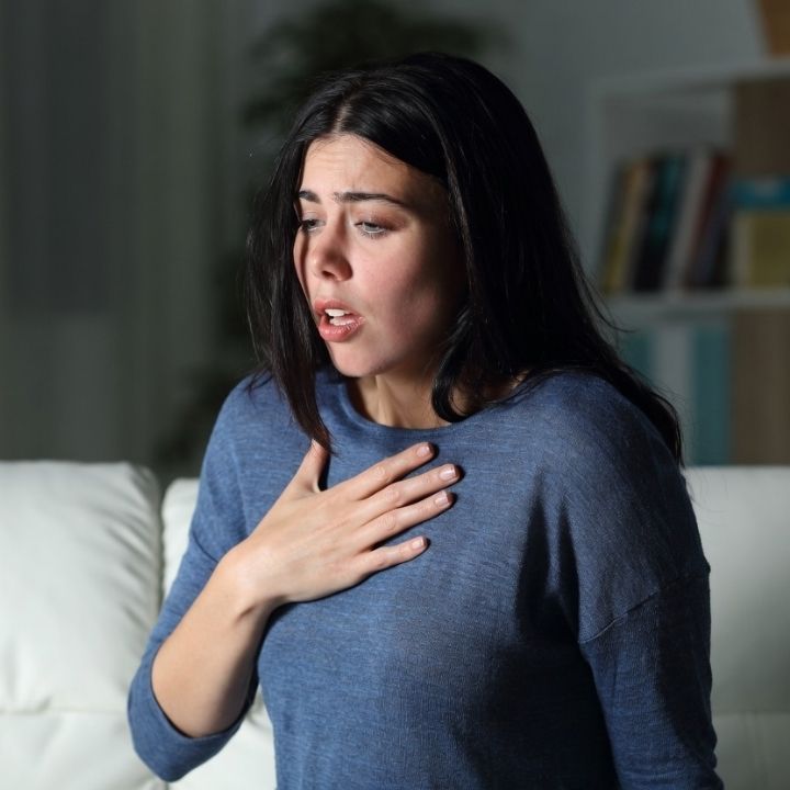 Woman experiencing anxiety attack with hand on chest.