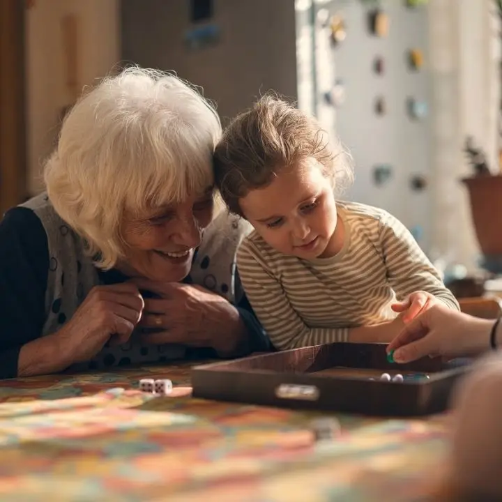 Grandparent and child enjoying a board game together at home.